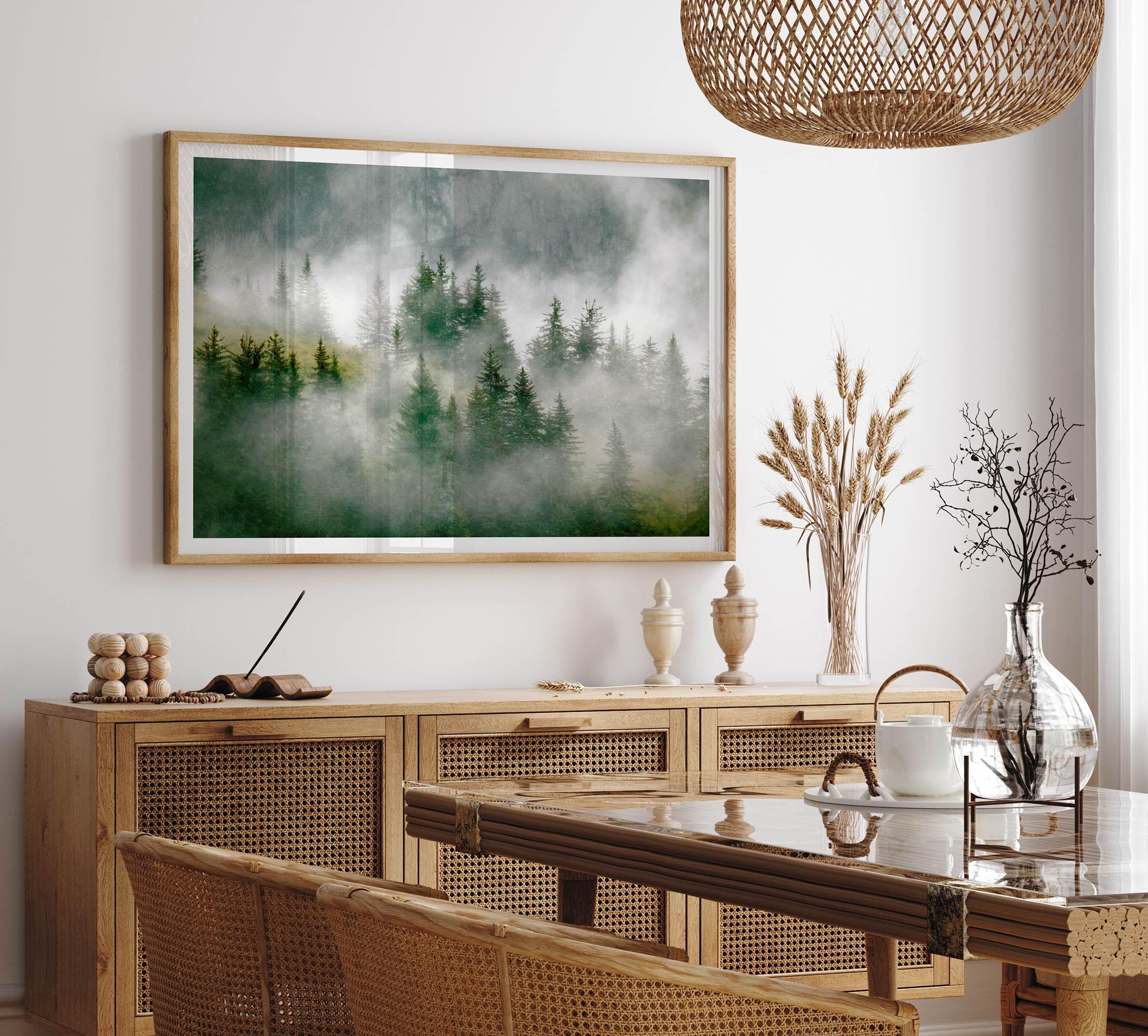 Fine art photography of a misty forest in Alaska, with the tops of trees on a mountain shrouded in white dreamlike fog.