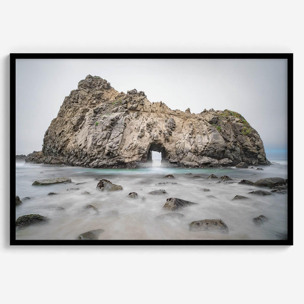 Fine art print showcasing a magnificent rock formation framing the horizon and crashing waves, with scattered rocks adding texture. Captivating and soothing, this print is a timeless addition to any space, evoking relaxation and awe-inspiring beauty.