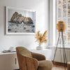 Fine art print showcasing a magnificent rock formation framing the horizon and crashing waves, with scattered rocks adding texture. Captivating and soothing, this print is a timeless addition to any space, evoking relaxation and awe-inspiring beauty.