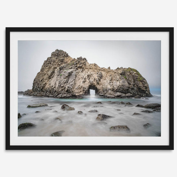 Fine art print showcasing a magnificent rock formation framing the horizon and crashing waves, with scattered rocks adding texture. Captivating and soothing, this print is a timeless addition to any space, evoking relaxation and awe-inspiring beauty.