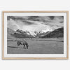 A black and white mountain horse fine art print that can come framed on unframed and was taken in Peru. This mountain wall art showcases snow-covered mountains in Peru and a charming horse grazing relaxingly in the forefront of the picture.