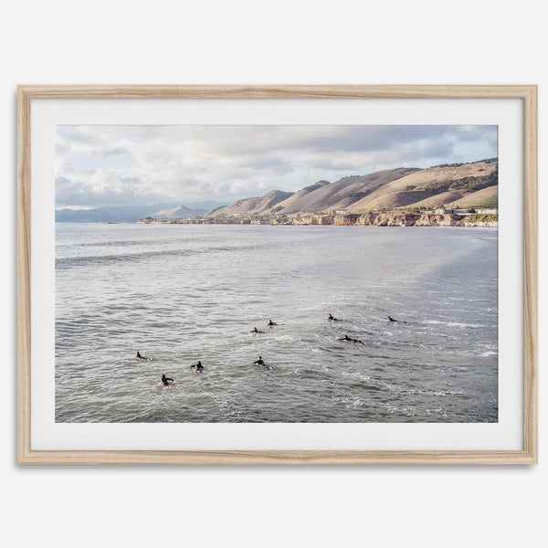 Surfers paddling near Pismo Beach captured in a fine art photography print with coastal cliffs and serene ocean views.