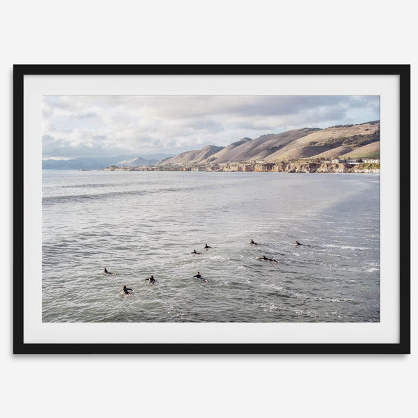 Surfers paddling near Pismo Beach captured in a fine art photography print with coastal cliffs and serene ocean views.