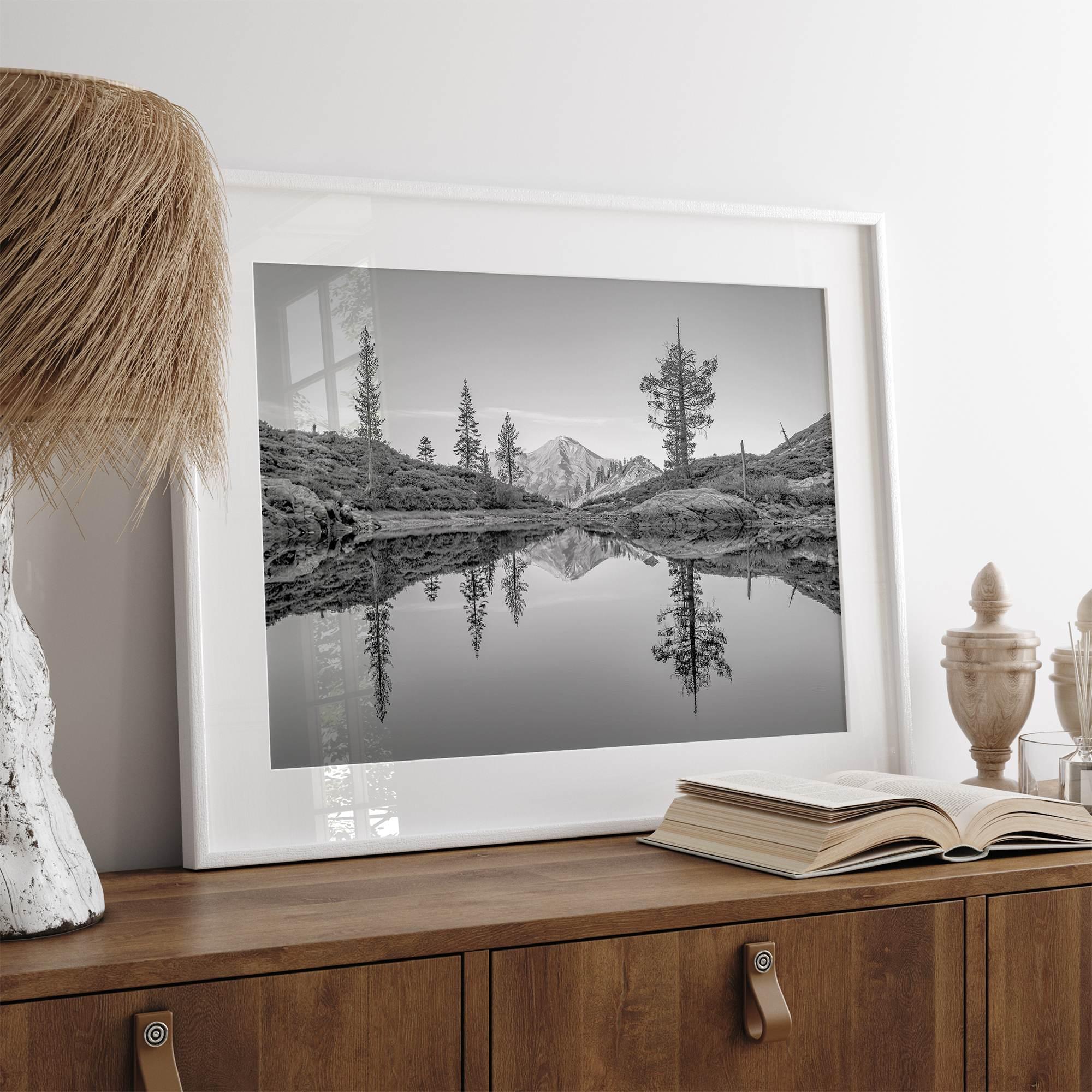 Black and white fine art photo of a serene mountain and forest mirrored in a still lake at sunset.