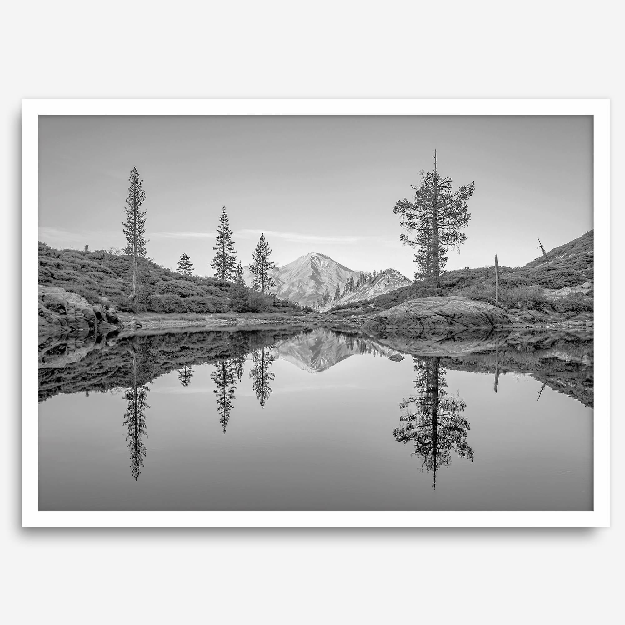 Black and white fine art photo of a serene mountain and forest mirrored in a still lake at sunset.