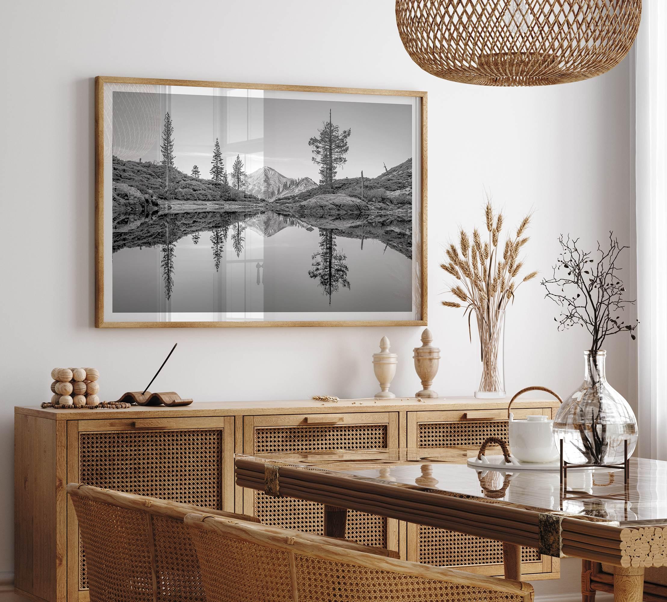 Black and white fine art photo of a serene mountain and forest mirrored in a still lake at sunset.