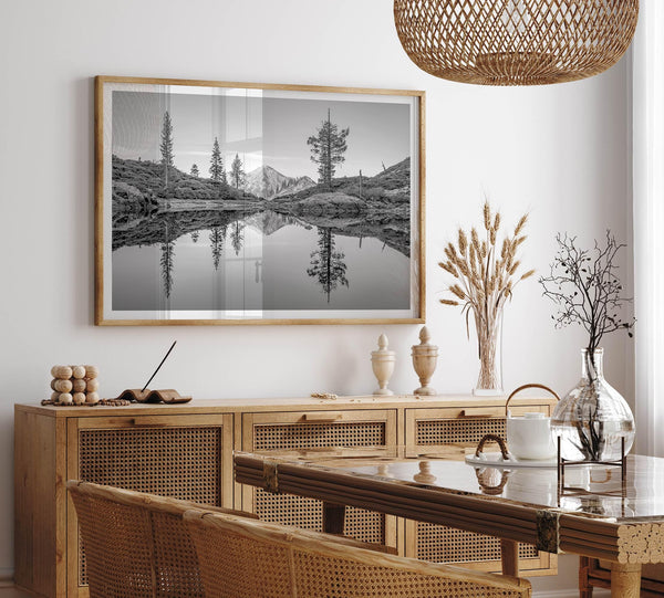 Black and white fine art photo of a serene mountain and forest mirrored in a still lake at sunset.