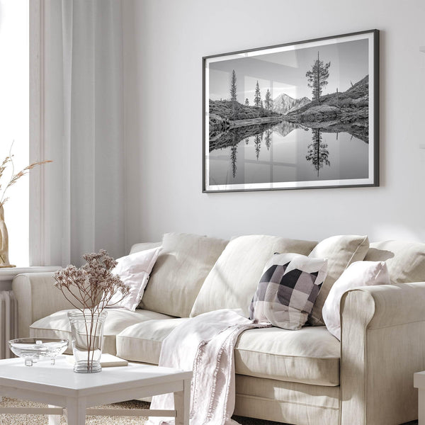 Black and white fine art photo of a serene mountain and forest mirrored in a still lake at sunset.