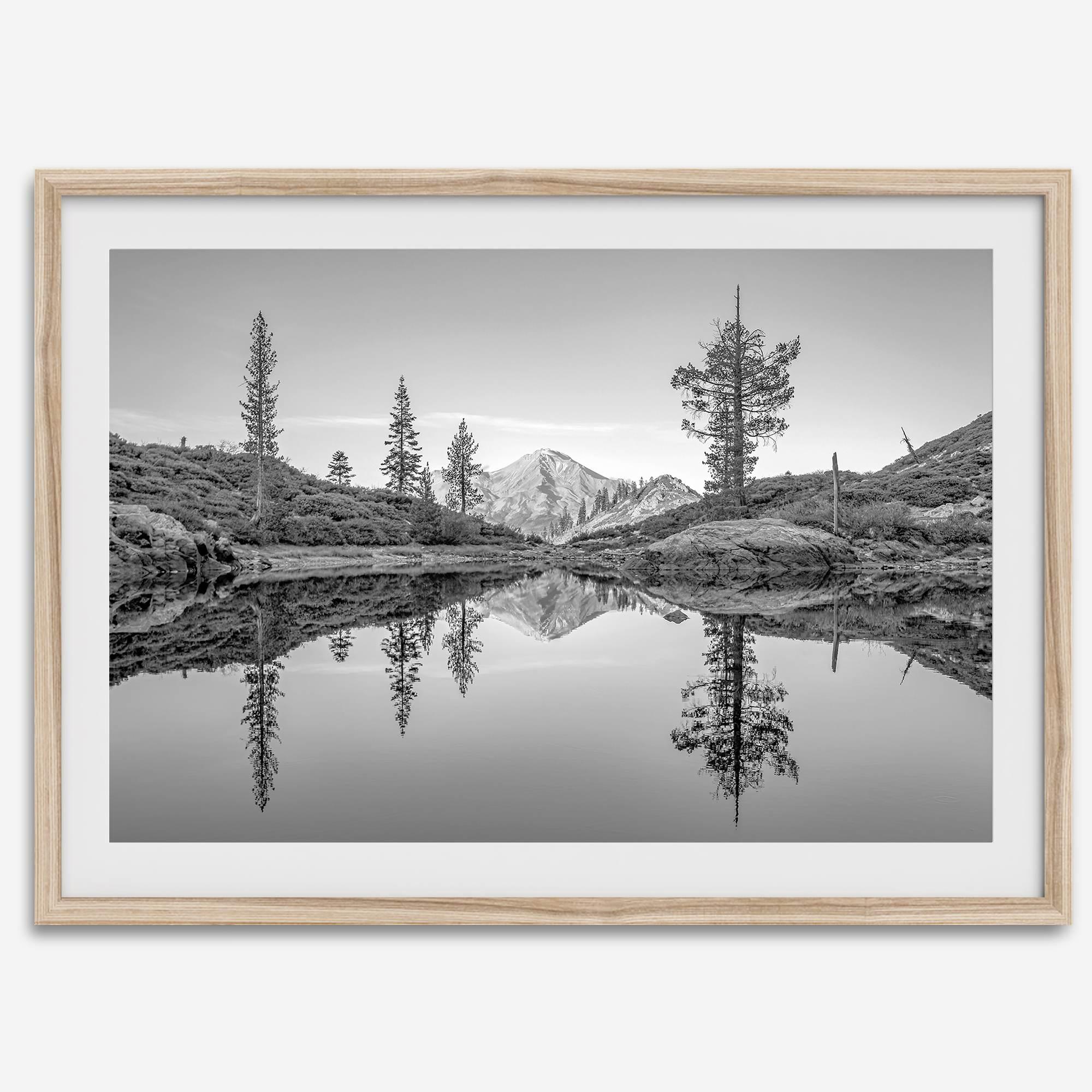 Black and white fine art photo of a serene mountain and forest mirrored in a still lake at sunset.