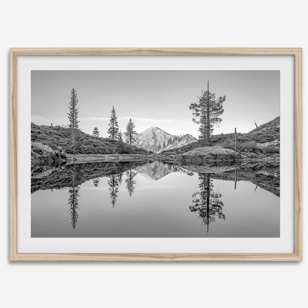 Black and white fine art photo of a serene mountain and forest mirrored in a still lake at sunset.