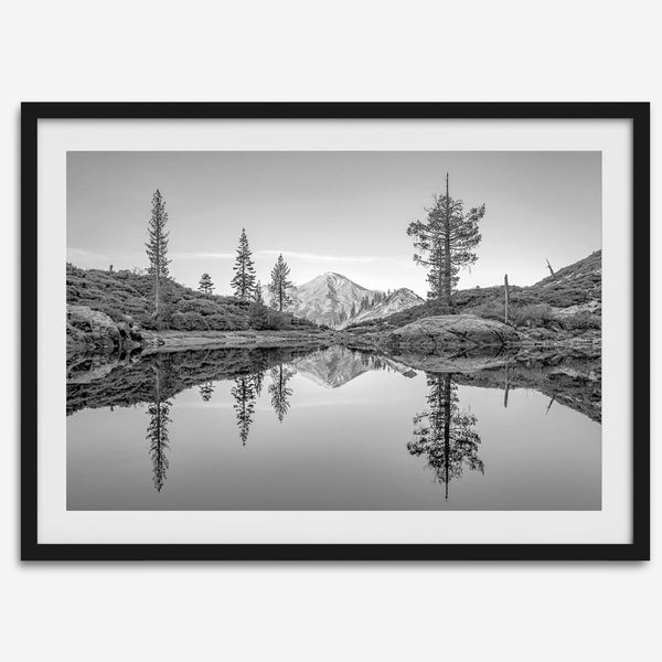 Black and white fine art photo of a serene mountain and forest mirrored in a still lake at sunset.