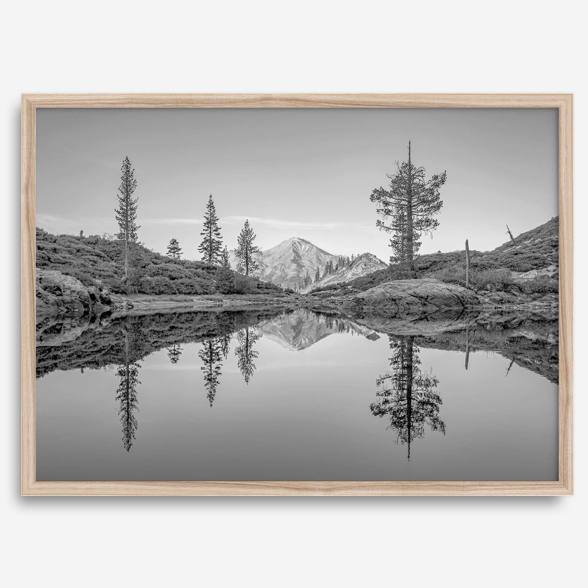 Black and white fine art photo of a serene mountain and forest mirrored in a still lake at sunset.