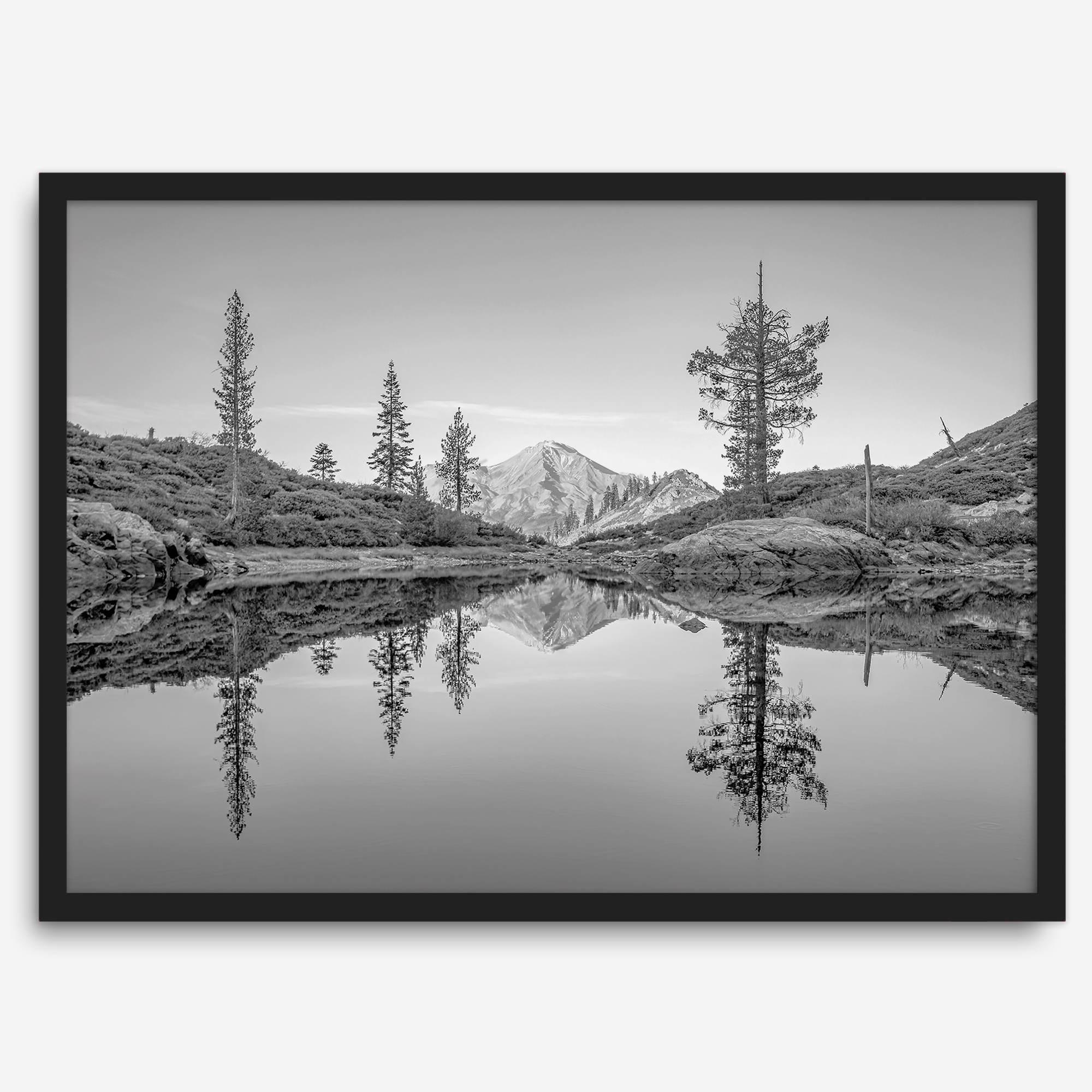 Black and white fine art photo of a serene mountain and forest mirrored in a still lake at sunset.