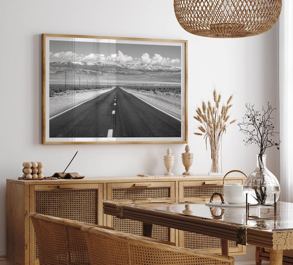 This stunning piece of black and white desert wall art will take your breath away. A beautifully framed picture of a Death Valley National Park road leading towards the snow-covered mountains at the end of the desert.