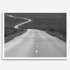 Black and white fine art photo of a winding desert road stretching through a vast minimalist landscape.
