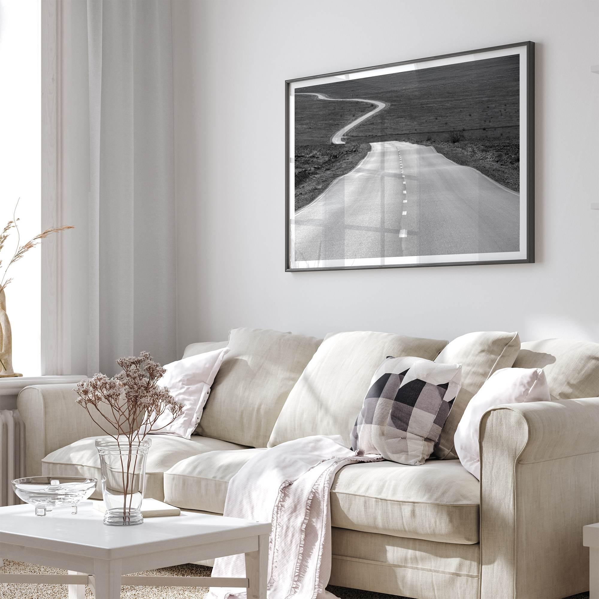 Black and white fine art photo of a winding desert road stretching through a vast minimalist landscape.