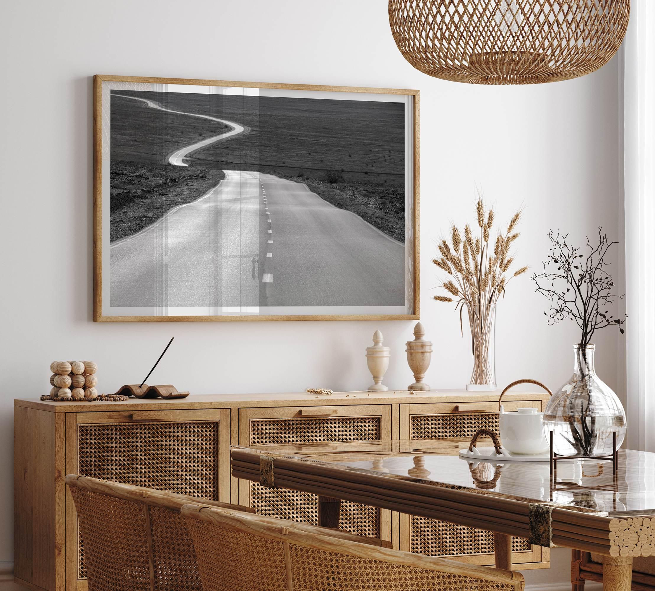 Black and white fine art photo of a winding desert road stretching through a vast minimalist landscape.