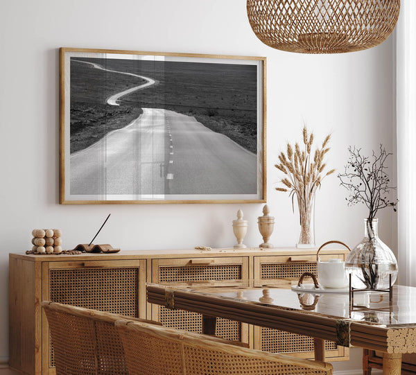 Black and white fine art photo of a winding desert road stretching through a vast minimalist landscape.