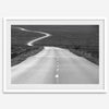 Black and white fine art photo of a winding desert road stretching through a vast minimalist landscape.