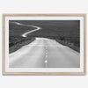 Black and white fine art photo of a winding desert road stretching through a vast minimalist landscape.