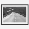 Black and white fine art photo of a winding desert road stretching through a vast minimalist landscape.