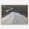 Black and white fine art photo of a winding desert road stretching through a vast minimalist landscape.