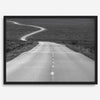 Black and white fine art photo of a winding desert road stretching through a vast minimalist landscape.