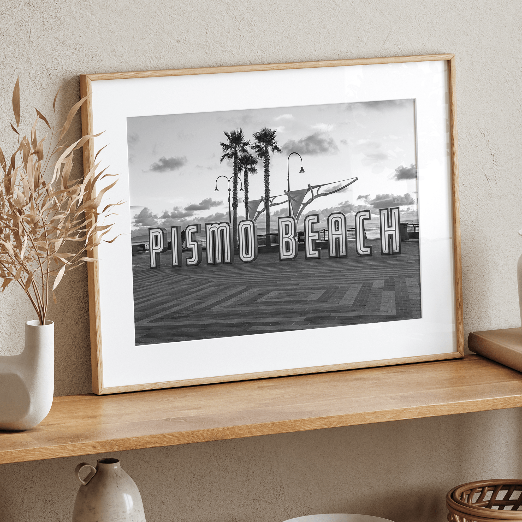 Black and white photo of the Pismo Beach street sign with palm trees and boardwalk – fine art coastal print