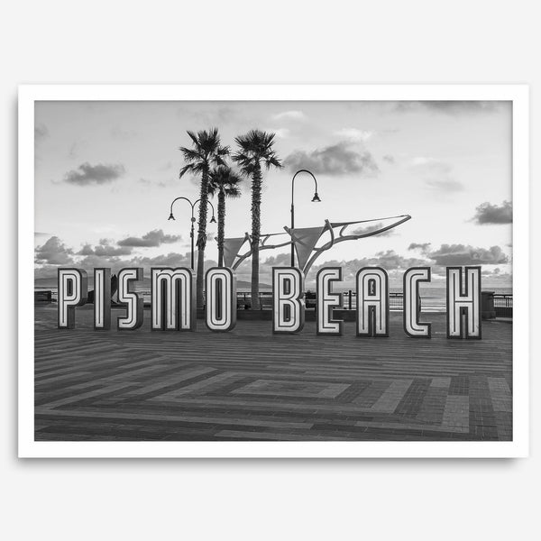 Black and white photo of the Pismo Beach street sign with palm trees and boardwalk – fine art coastal print