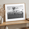 Black and white photo of the Pismo Beach street sign with palm trees and boardwalk – fine art coastal print