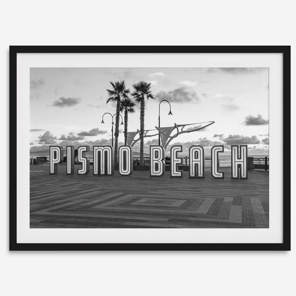 Black and white photo of the Pismo Beach street sign with palm trees and boardwalk – fine art coastal print