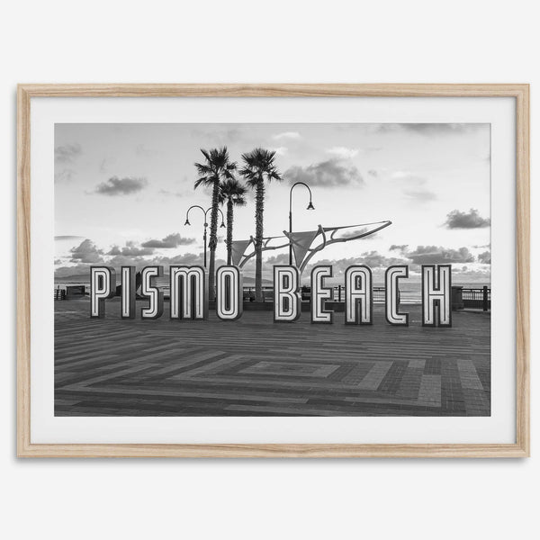Black and white photo of the Pismo Beach street sign with palm trees and boardwalk – fine art coastal print
