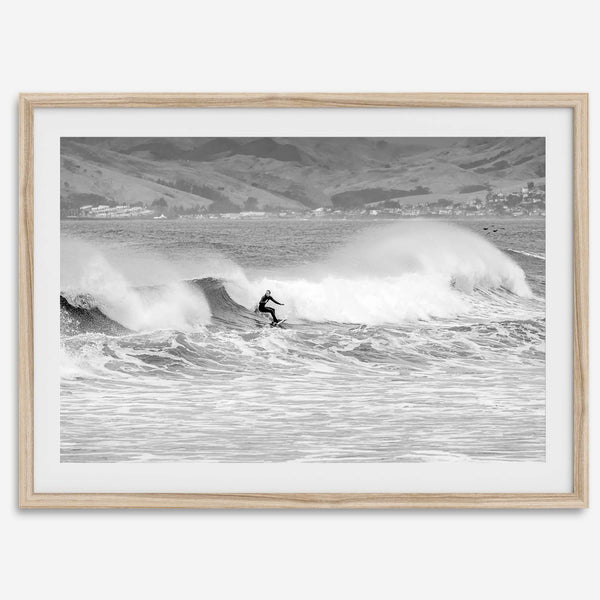 A black and white fine art surf print featuring a lone surfer riding the waves in Pismo Beach, California.