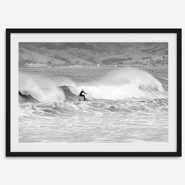 A black and white fine art surf print featuring a lone surfer riding the waves in Pismo Beach, California.