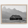 Step into Grand Teton National Park with this fine art black and white mountain print. This western landscape photo showcases a century-old rustic hut at the foot of the snowy, pointy Teton mountains.