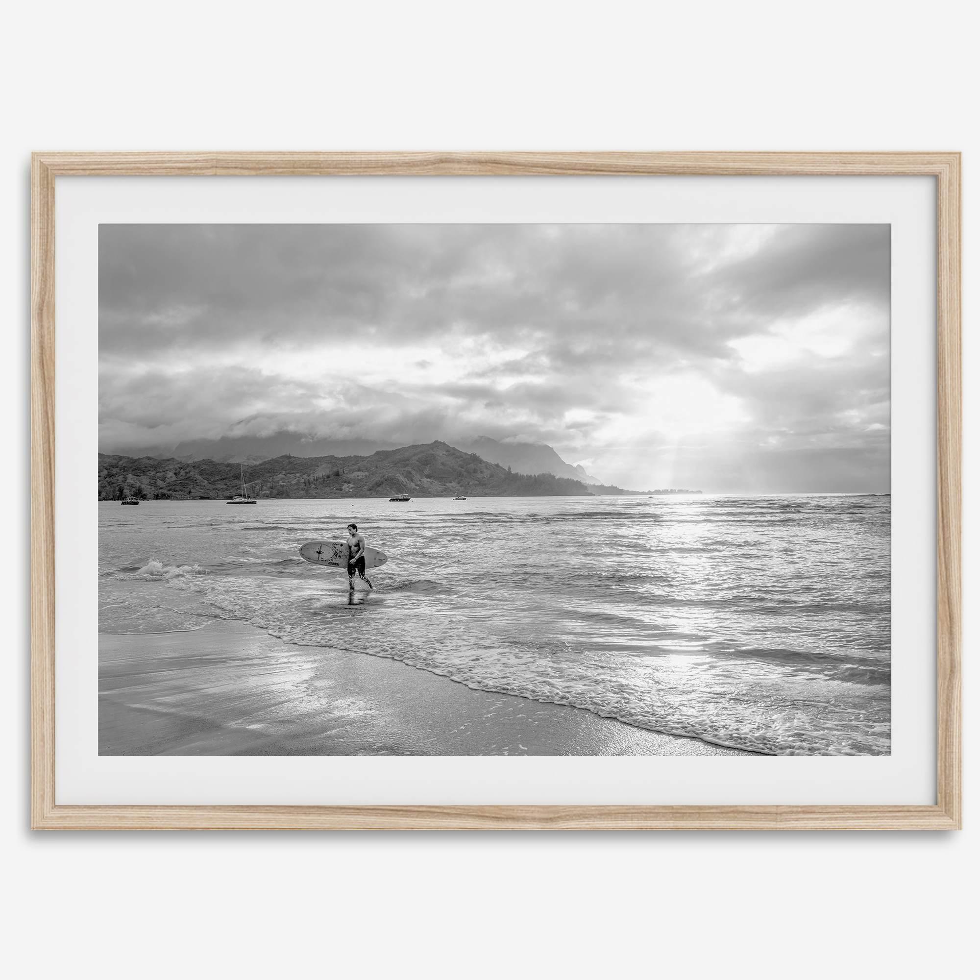 Surfer Wall Art featuring a lone surfer emerging from the ocean at Hanalei Bay in black-and-white photography.