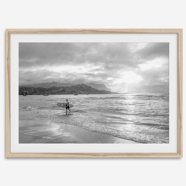 Surfer Wall Art featuring a lone surfer emerging from the ocean at Hanalei Bay in black-and-white photography.