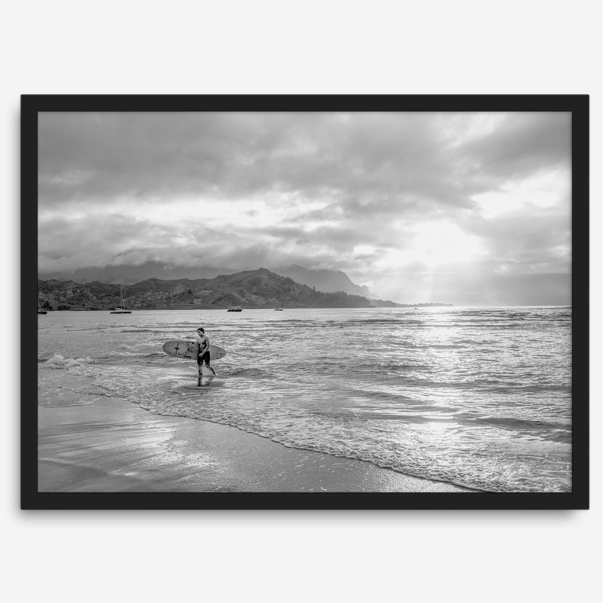Surfer Wall Art featuring a lone surfer emerging from the ocean at Hanalei Bay in black-and-white photography.