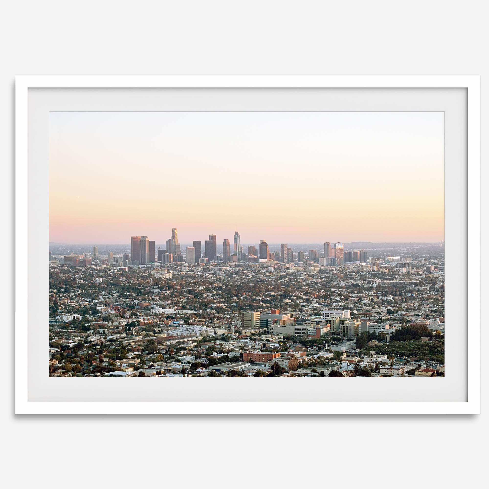 Los Angeles cityscape bathed in a vibrant sunset, showcasing the city's iconic buildings from above