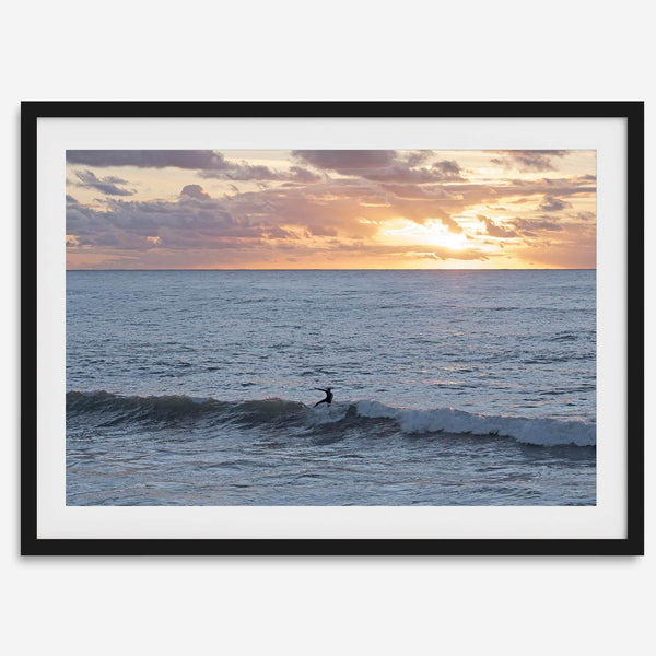 A fine art ocean sunset print showcasing a serene sunset and a lone surfer riding the waves. Taken in Montana De Oro State Park, California.