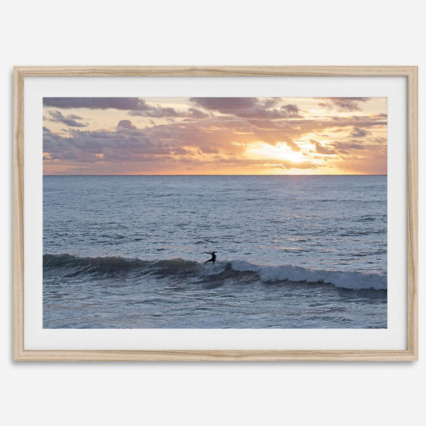 A fine art ocean sunset print showcasing a serene sunset and a lone surfer riding the waves. Taken in Montana De Oro State Park, California.
