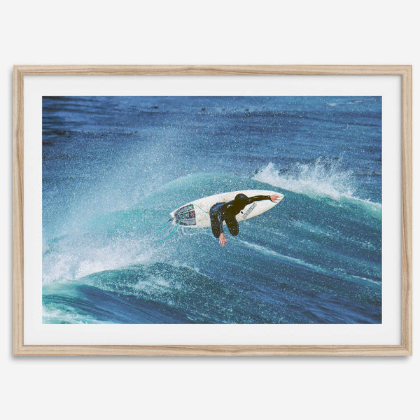 Surfer flying above a turquoise wave in Santa Cruz captured in vibrant ocean photography.