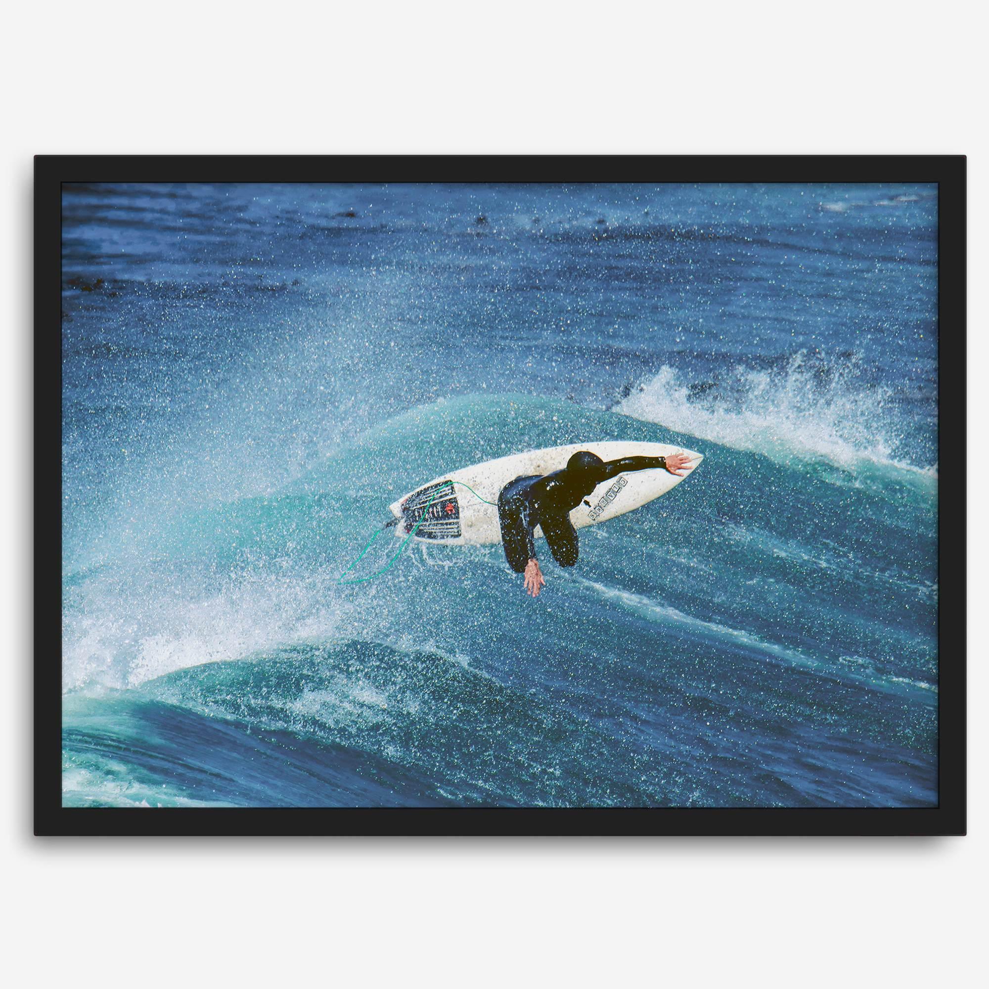 Surfer flying above a turquoise wave in Santa Cruz captured in vibrant ocean photography.