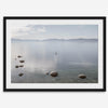 Fine art photography print of Lake Tahoe featuring a serene blue water surrounded by Pacific Northwest mountains, with a lone stand-up paddle silhouette on the lake.
