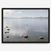 Fine art photography print of Lake Tahoe featuring a serene blue water surrounded by Pacific Northwest mountains, with a lone stand-up paddle silhouette on the lake.