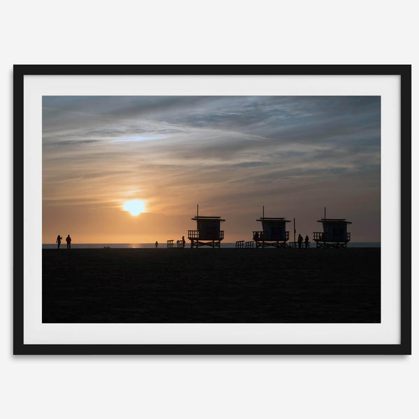 Step into Venice Beach with our fine art beach sunset framed or unframed print. The print showcases the beach in sunset with the silhouettes of the famous lifeguard towers and people in the sunset.