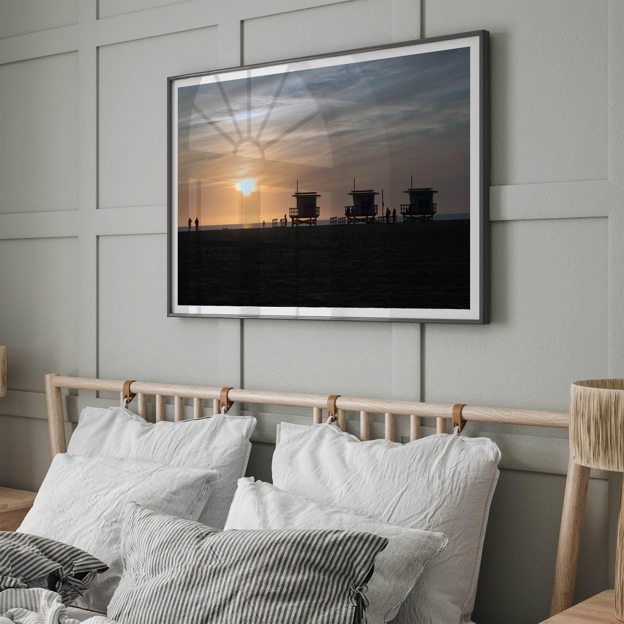 Step into Venice Beach with our fine art beach sunset framed or unframed print. The print showcases the beach in sunset with the silhouettes of the famous lifeguard towers and people in the sunset.