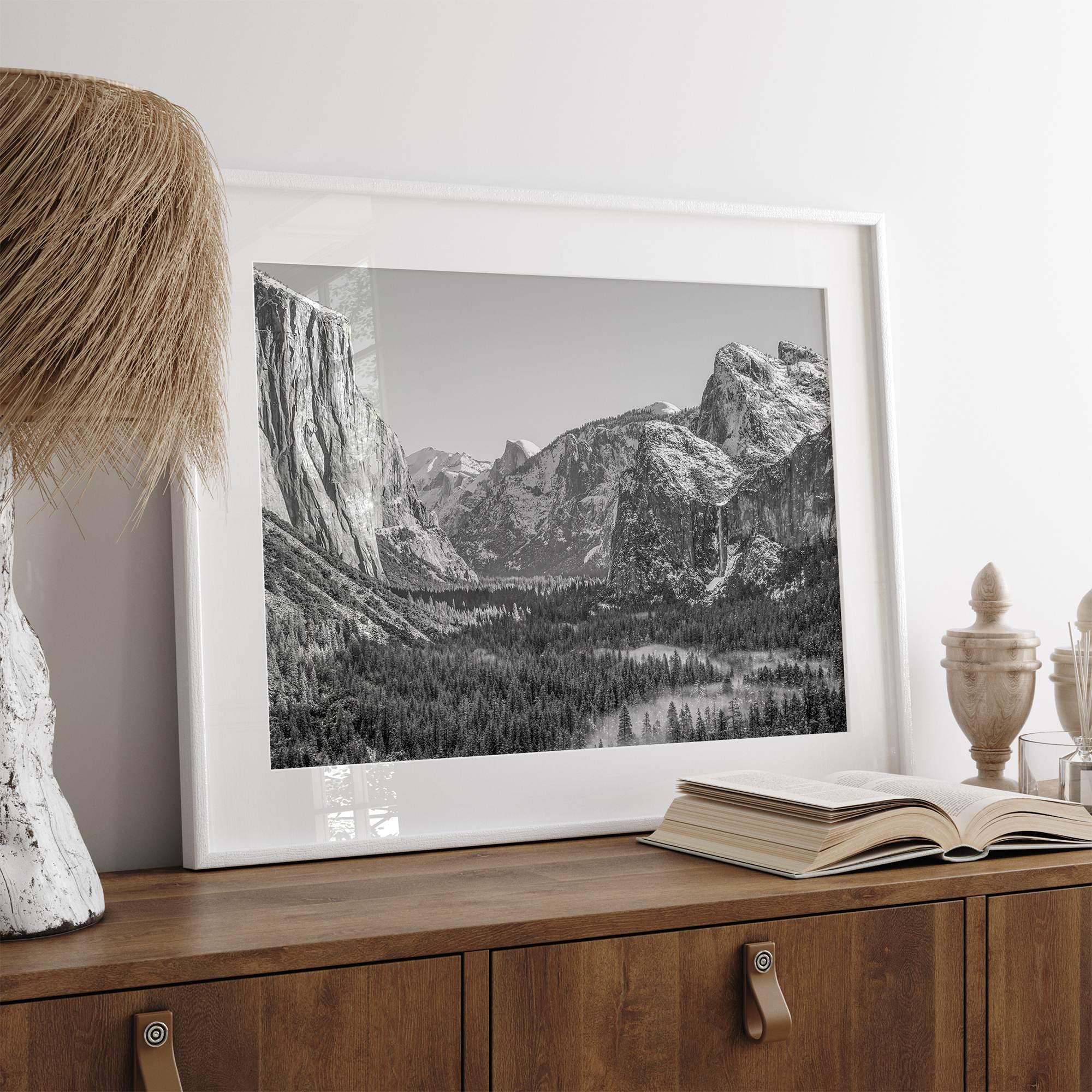 A fine art Yosemite Print featuring Yosemite Valley covered in snow in winter and a beautiful fog lays in the valley forest. This black and white mountain wall art is perfect for nature and fine art lovers.