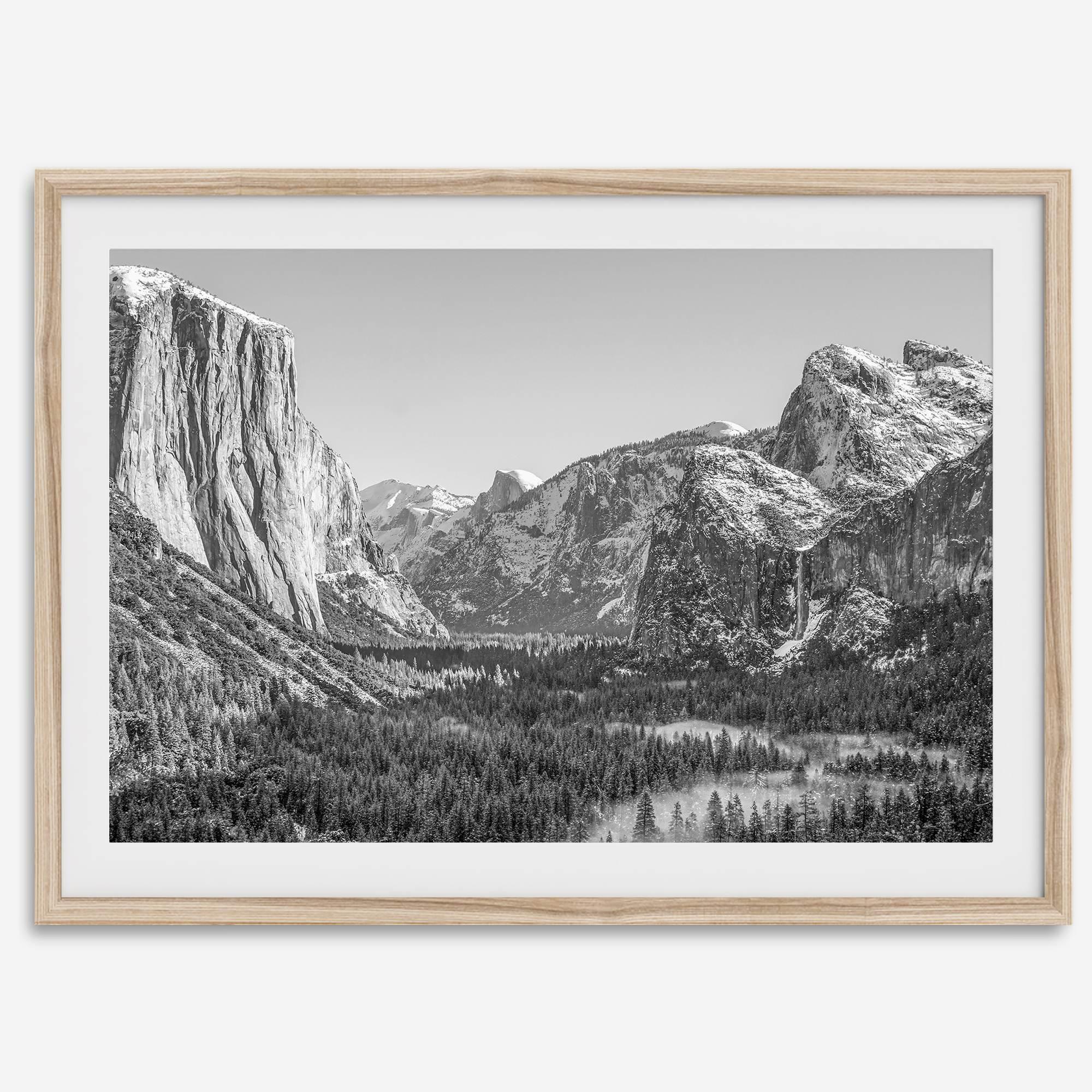 A fine art Yosemite Print featuring Yosemite Valley covered in snow in winter and a beautiful fog lays in the valley forest. This black and white mountain wall art is perfect for nature and fine art lovers.