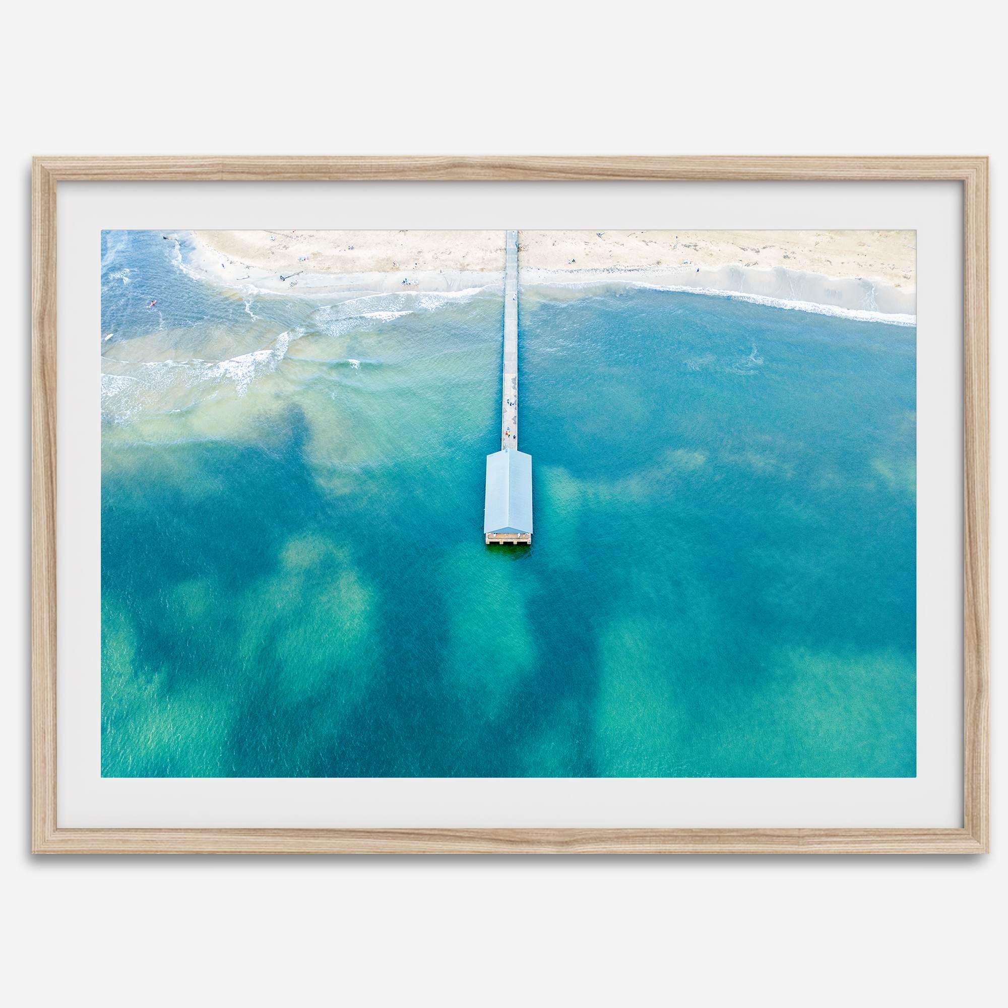 Drone photo of a pier extending into clear blue ocean at Hanalei Beach, Kauai, Hawaii.